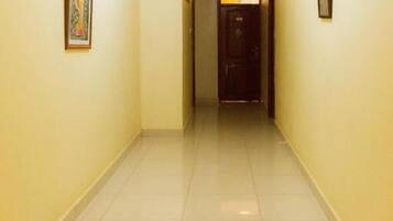 A hallway with tiled floors and walls, leading to a door at the end.