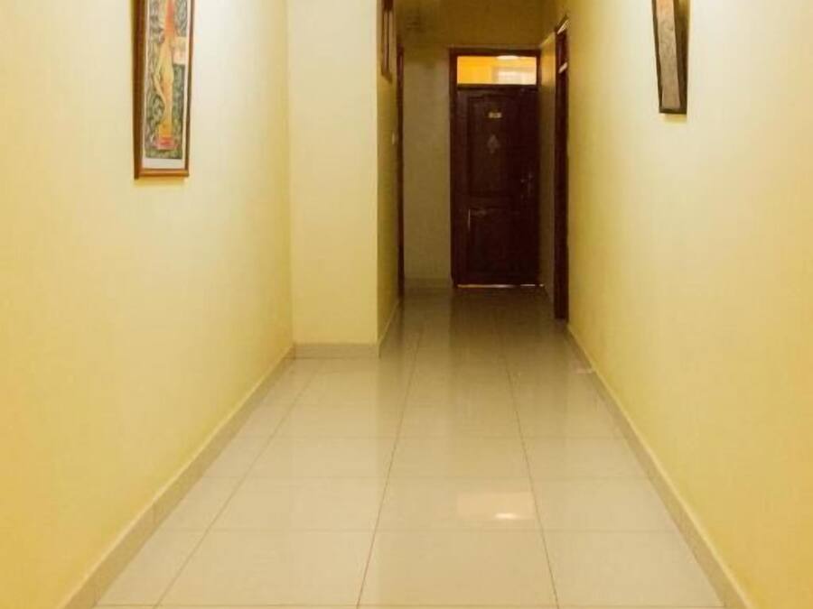 A hallway with tiled floors and walls, leading to a door at the end.