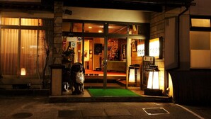 A traditional Japanese building with a green entrance mat, a statue, and a signboard. - Tsukasaya Ryokan (Tsuruoka)