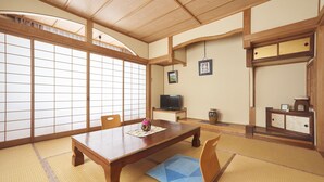 A traditional Japanese-style room with tatami flooring, a low wooden table, and sliding shoji doors. - Tsukasaya Ryokan (Tsuruoka)