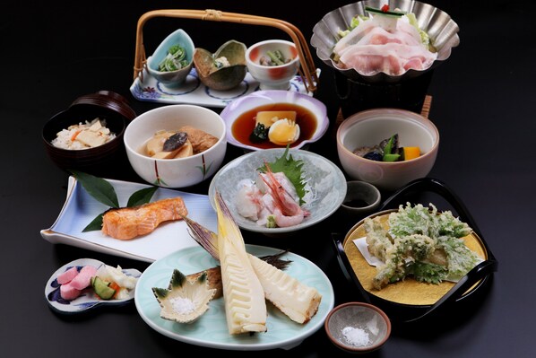 A variety of Japanese dishes including sushi, sashimi, and tempura, arranged on multiple plates and bowls. - Tsukasaya Ryokan (Tsuruoka)
