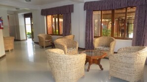 A spacious lobby with wicker furniture and large windows with purple curtains. - Kayegi Hotel (Mbale)