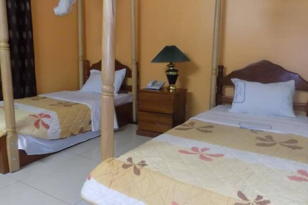 Una habitación con dos camas, una mesita de noche y una lámpara.