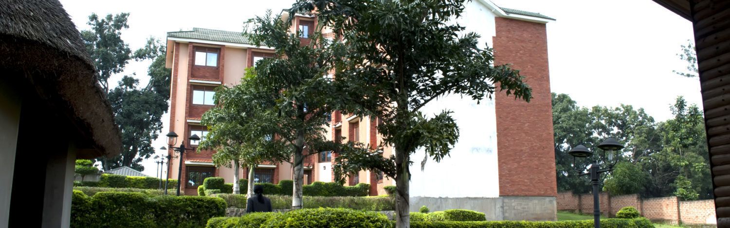 A multi-story building with a brick facade and a thatched-roof structure in the foreground.