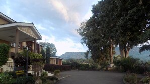 A building with a covered entrance, a sign indicating parking availability, and a view of a mountainous landscape. - Kayegi Hotel (Mbale)
