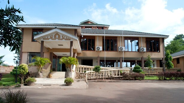 A two-story building with a covered entrance, multiple windows, and a paved driveway. - Kayegi Hotel (Mbale)