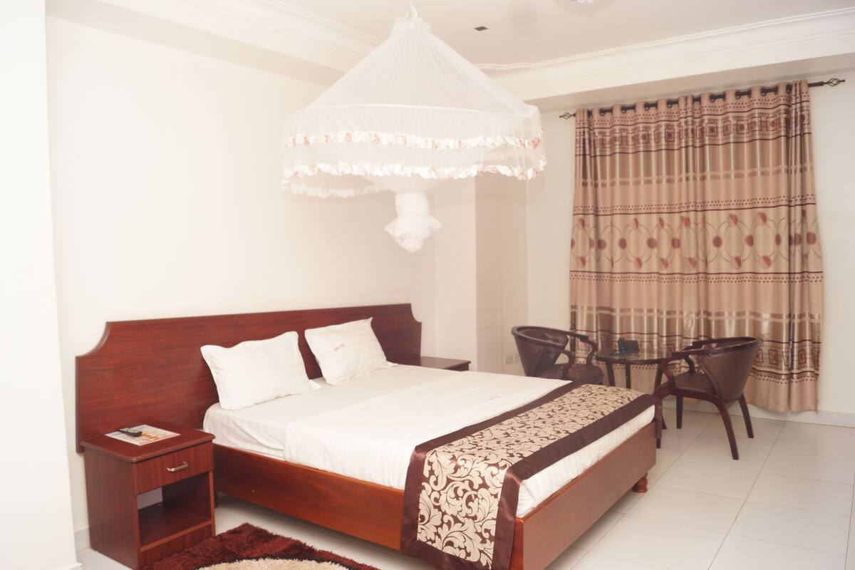 A bedroom with a wooden bed, bedside table, and a small table with chairs.