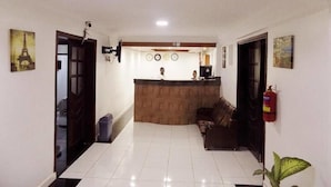 A reception area with a wooden counter, a fire extinguisher, and a reception desk. - Sunrise Hotel (Kampala)