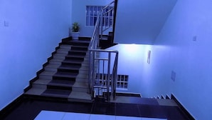 A staircase with a metal railing, a potted plant, and a small window. - Sunrise Hotel (Kampala)