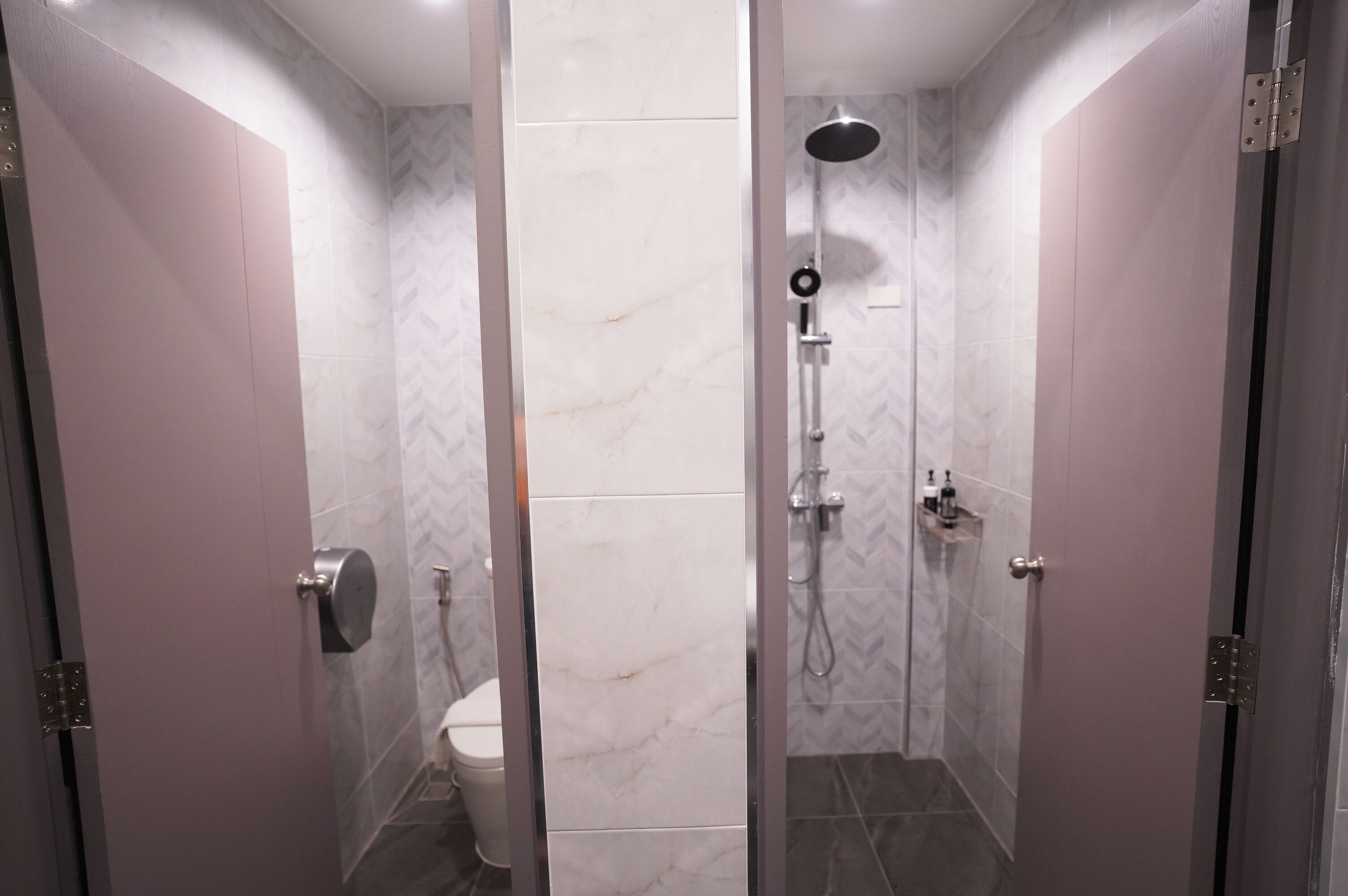 Een moderne badkamer met een douche, toilet en handdroger.