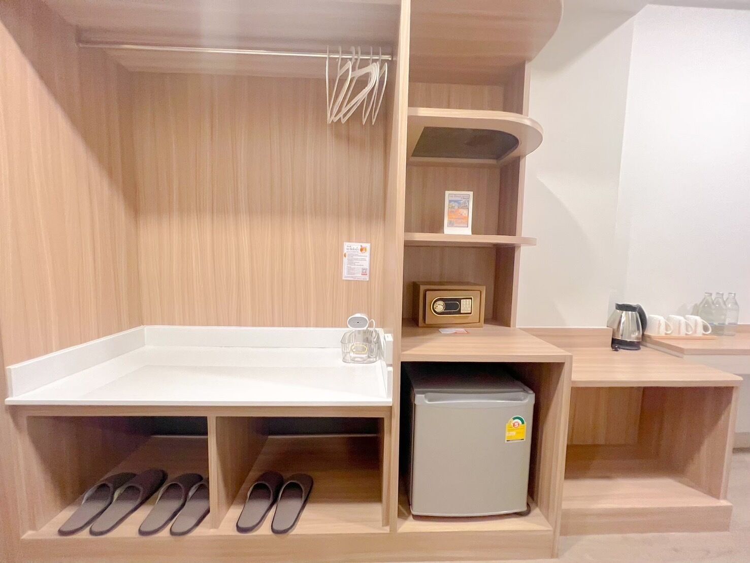 A compact kitchenette with a sink, a small refrigerator, and shelves with various items.
