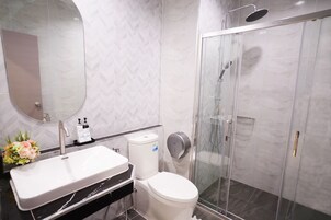 Un baño moderno con lavamanos, inodoro y ducha blancos.