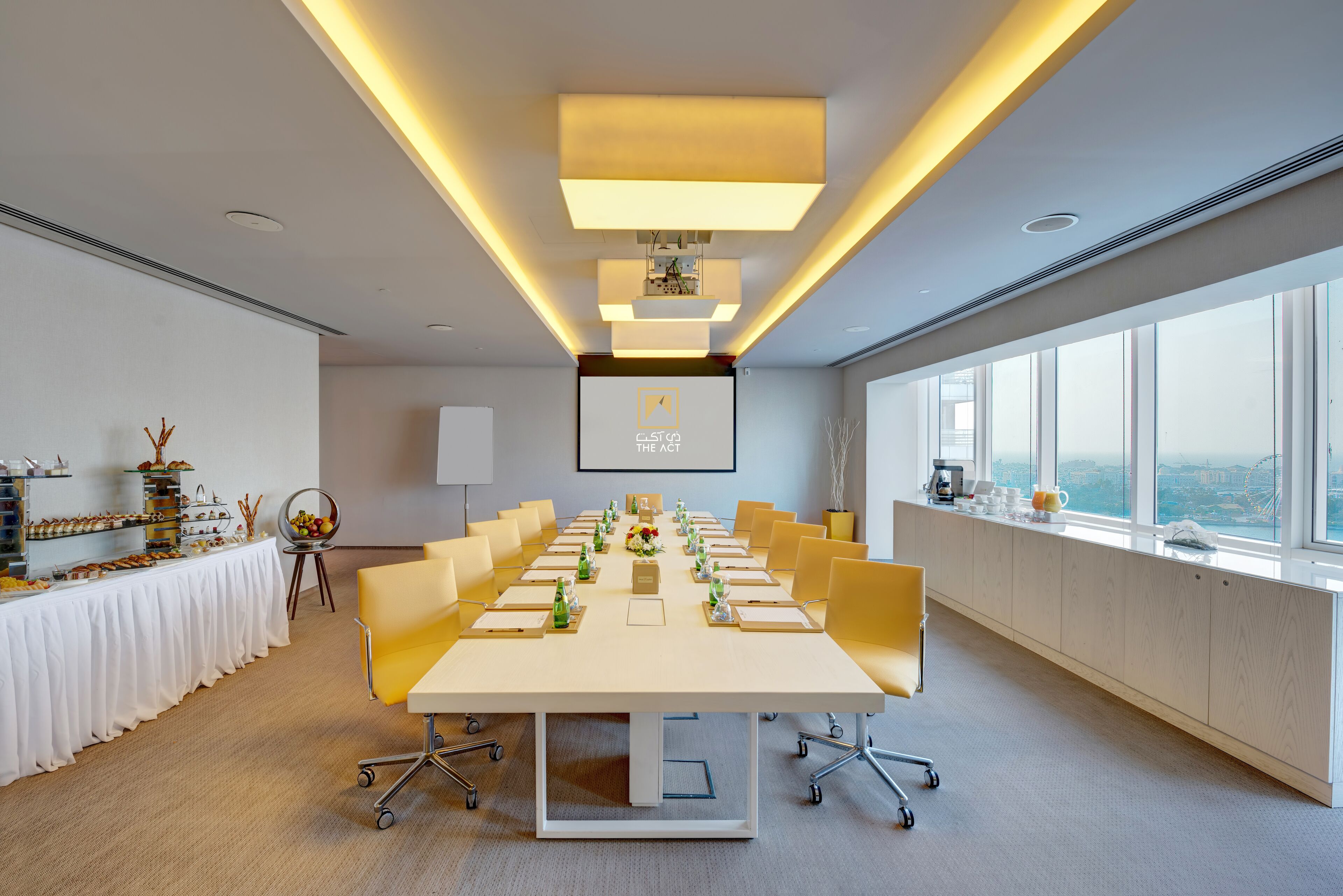 A modern conference room with a long table, yellow chairs, and a city view through large windows.