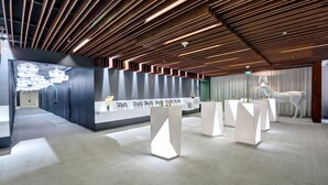 A modern reception area with a sleek design, featuring a reception desk, seating area, and a decorative horse statue. - The Act Hotel Sharjah (Sharjah)