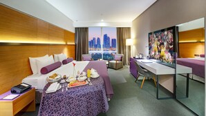 A hotel room with a bed, desk, and a large window with a city view. - The Act Hotel Sharjah (Sharjah)