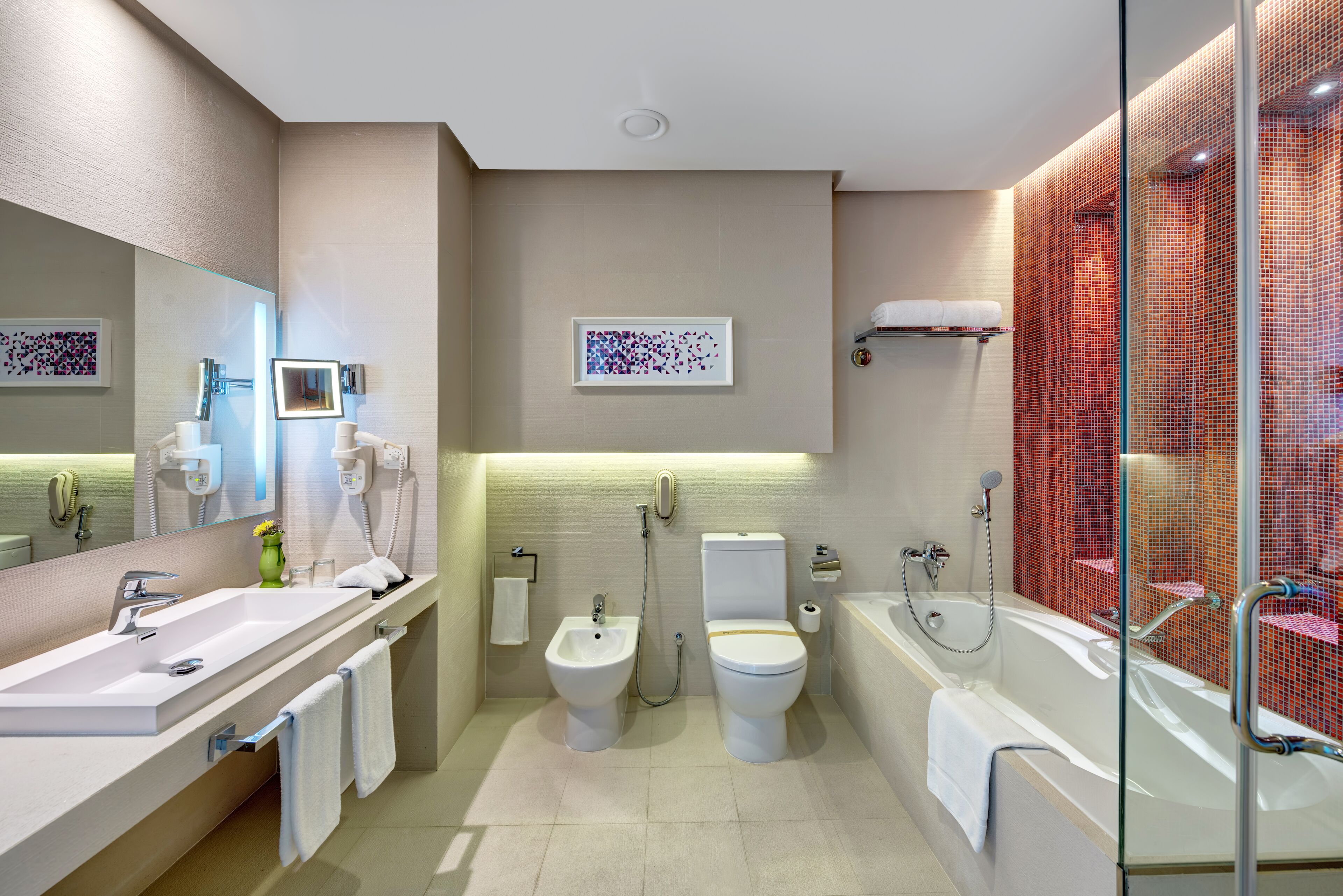 A modern bathroom with a large sink, bidet, toilet, and bathtub.