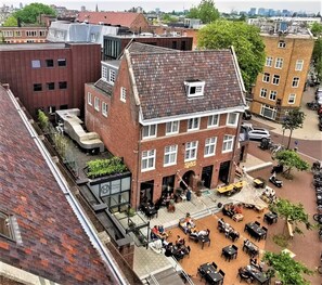 A building with a courtyard featuring outdoor seating, a visible restaurant, and a clock tower.