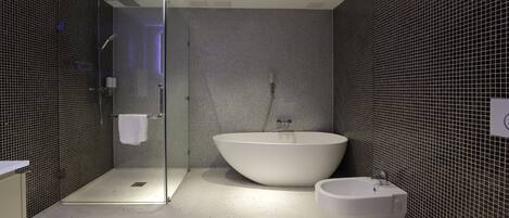 A modern bathroom with a glass shower enclosure, a freestanding bathtub, and a toilet.