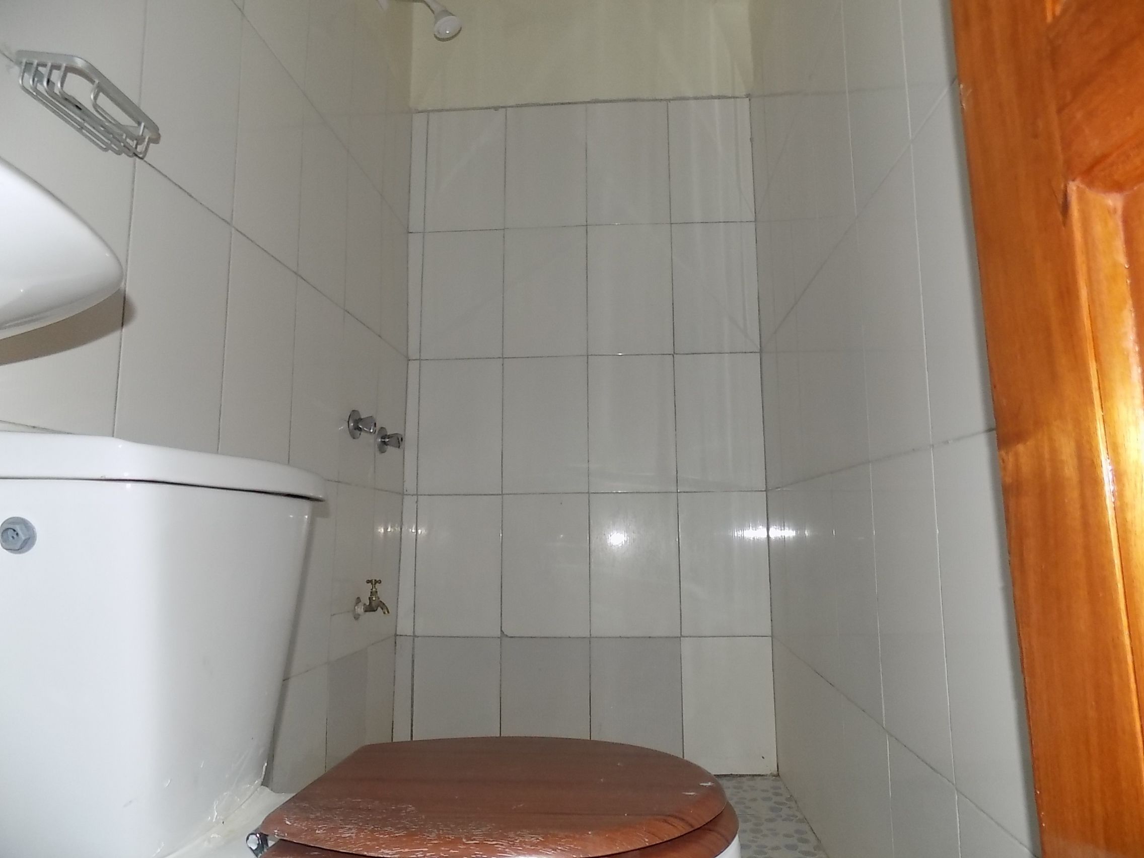 Un baño pequeño y cerrado con inodoro, lavamanos y ducha.