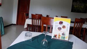 Un comedor con sillas de madera, una mesa con un menú y un extintor en la pared.