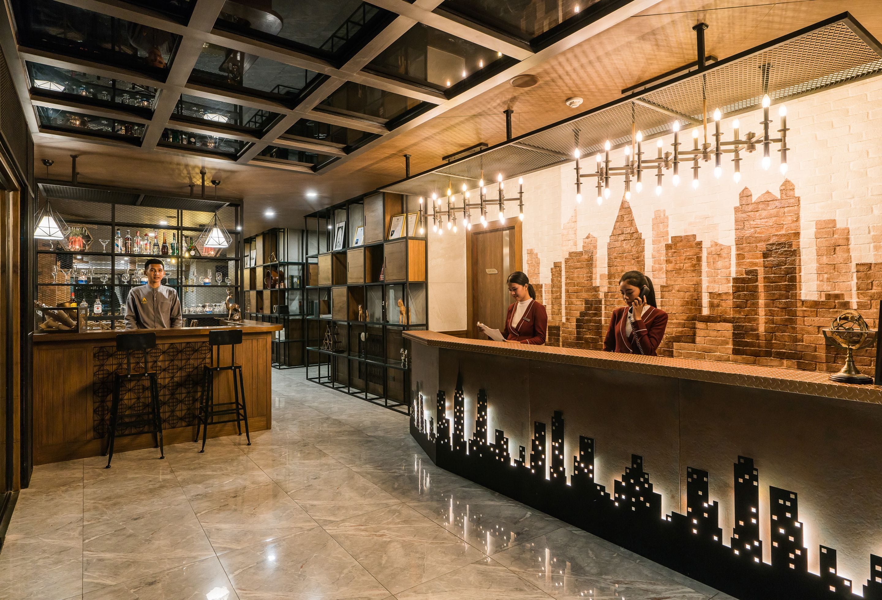 A modern bar area with a cityscape design on the counter, bar stools, and shelves with bottles.
