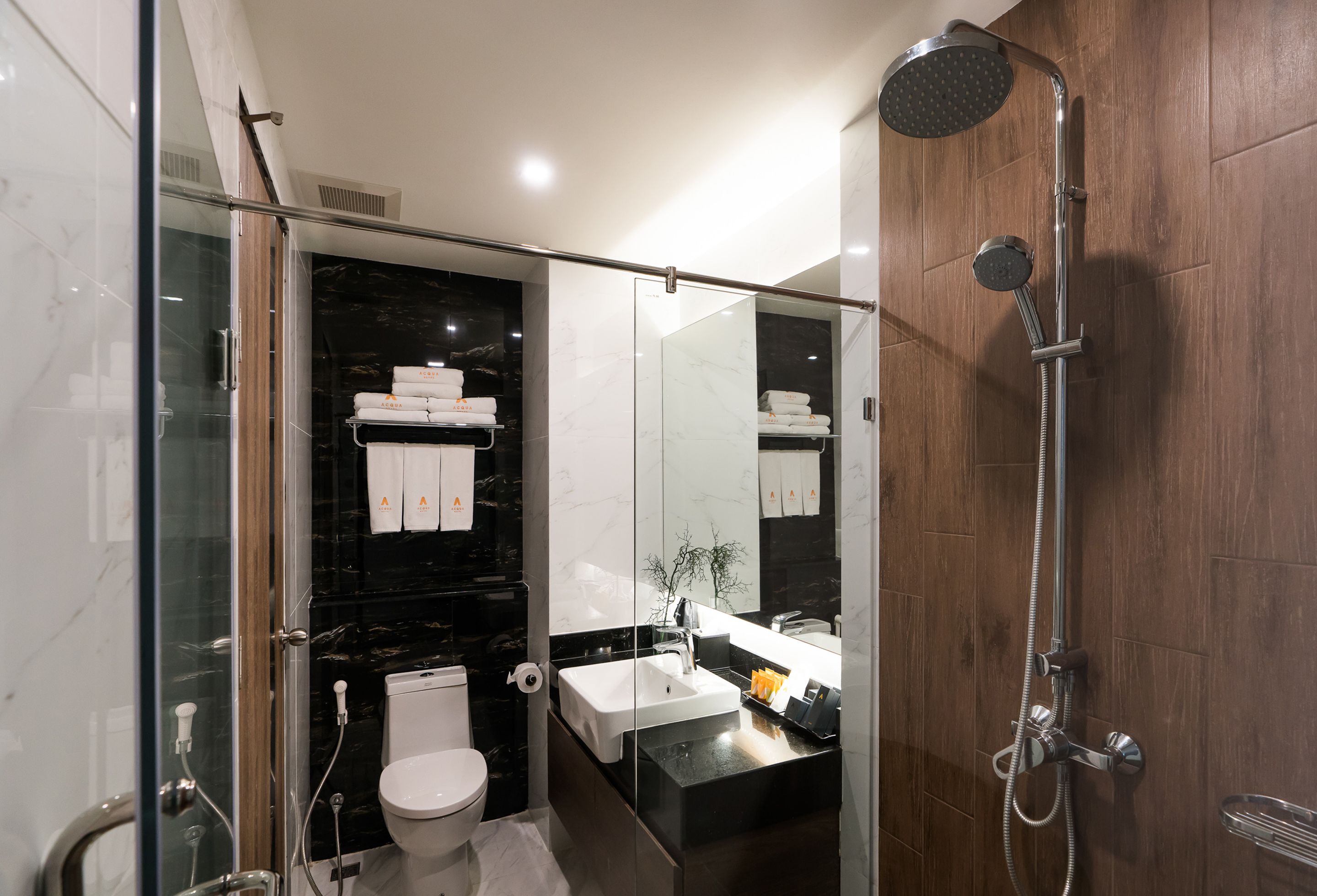 A modern bathroom with a glass shower enclosure, a white sink, and a dark marble backsplash.