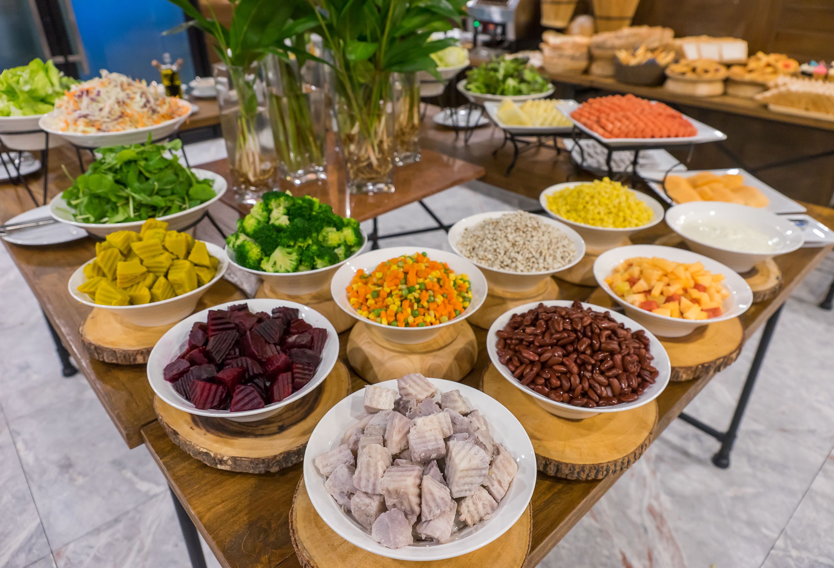 A buffet table with various dishes including salads, vegetables, and meats.