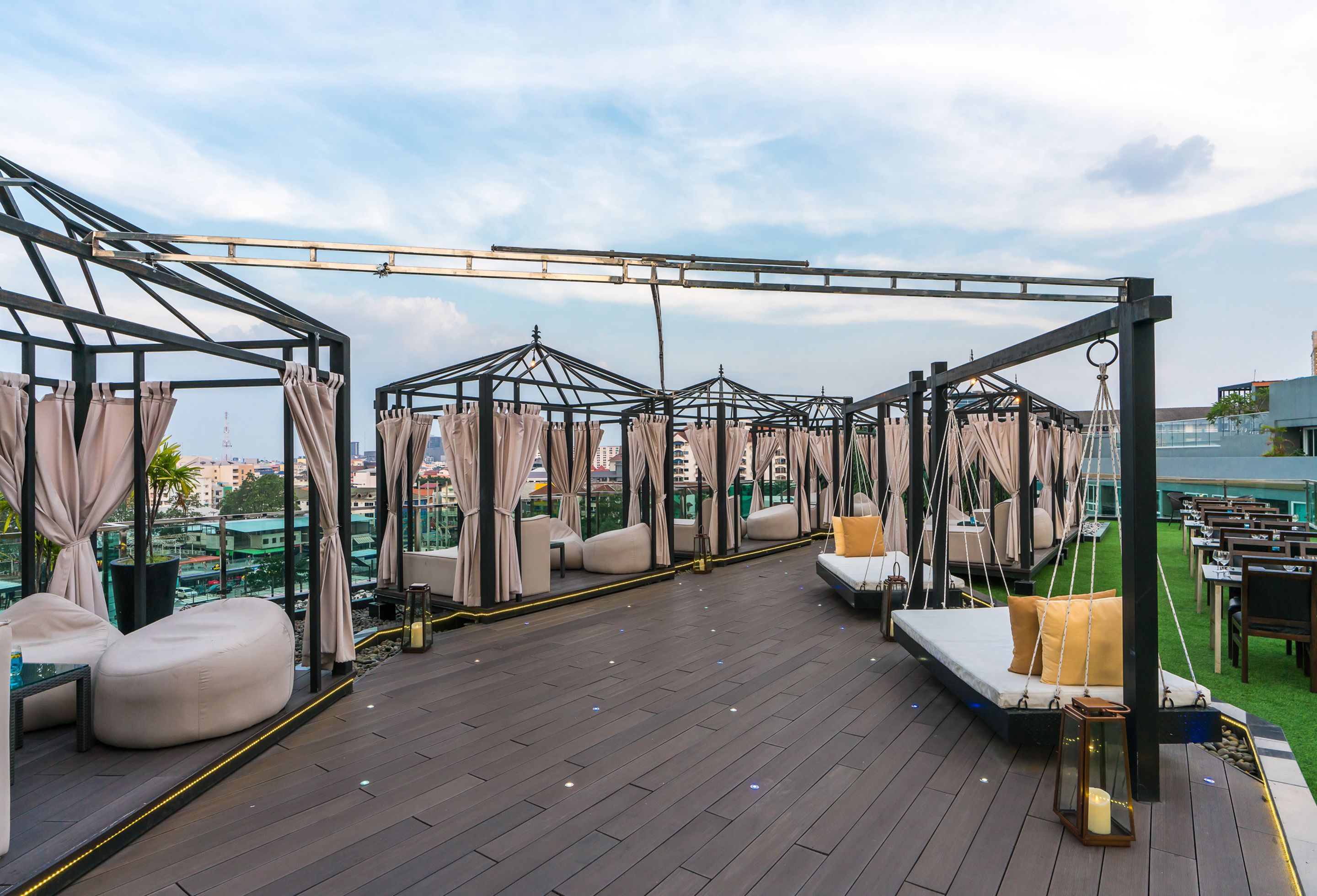 A rooftop terrace with cushioned seating areas, a pool, and a view of the city skyline.