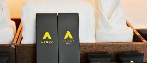 A hotel room with a bathtub, two black boxes with the logo 'ACQUA', and a white towel.