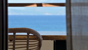 A wicker chair with a view of the ocean through a window. - Sunrise Hotel (Samos)