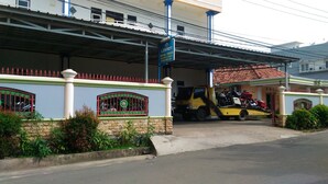 A building with a covered entrance, a signboard, and a parked tow truck. - Losmen Ibu Hj. Tarjo (Palembang)