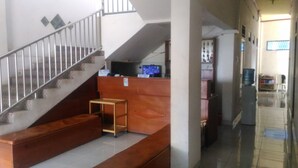 A staircase with a metal railing leading to a landing area with a wooden bench and a small table. - Losmen Ibu Hj. Tarjo (Palembang)