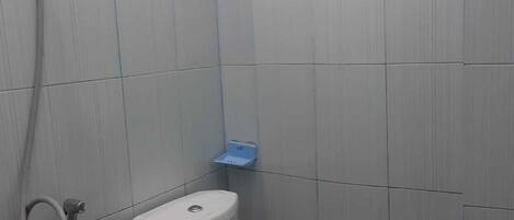 A small, enclosed bathroom with a toilet, a shower, and a towel rack.