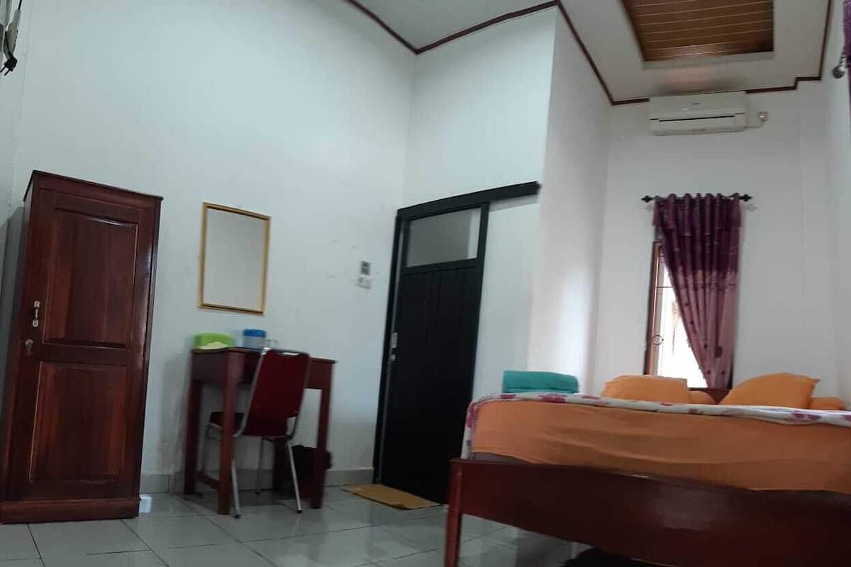 A room with a bed, a desk with a chair, a wardrobe, and a door.