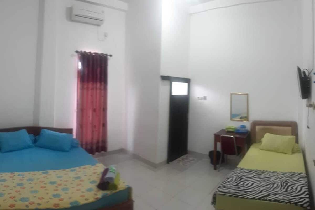 A room with two beds, a desk, and a mirror.