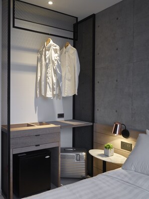 A modern hotel room with a bed, a small desk with a lamp, a mini-fridge, and a suitcase. - Monka Hotel (Taipei)