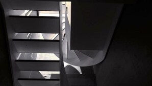Una escalera de caracol con diseño moderno, hecha de metal y hormigón, que conduce a un nivel superior.