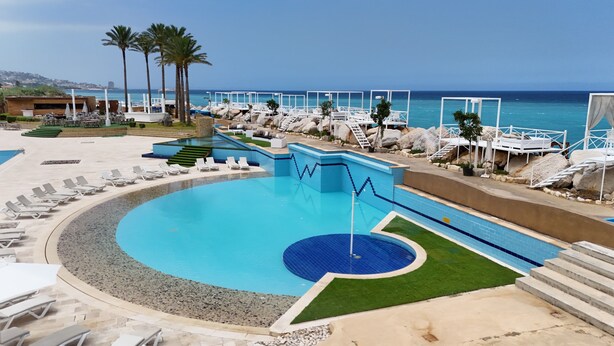 A pool area with lounge chairs, a basketball court, and a view of the ocean. - Four Seasons Halat (Halat)