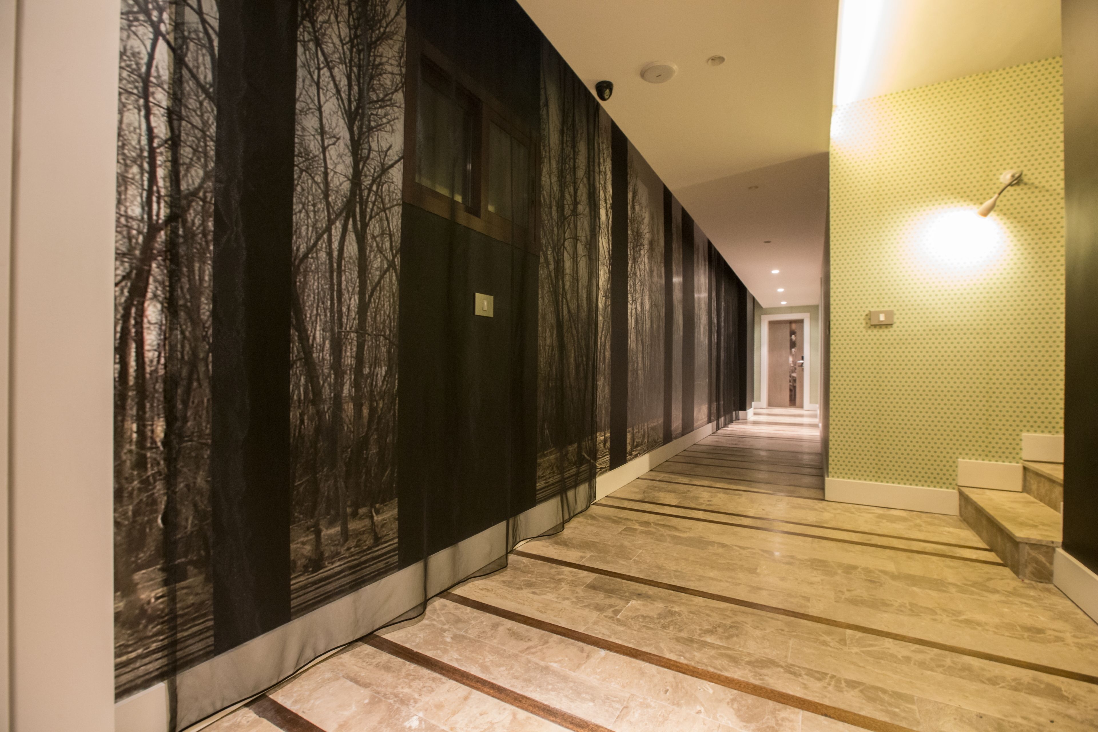 A long hallway with a patterned wall on one side and a plain wall on the other.