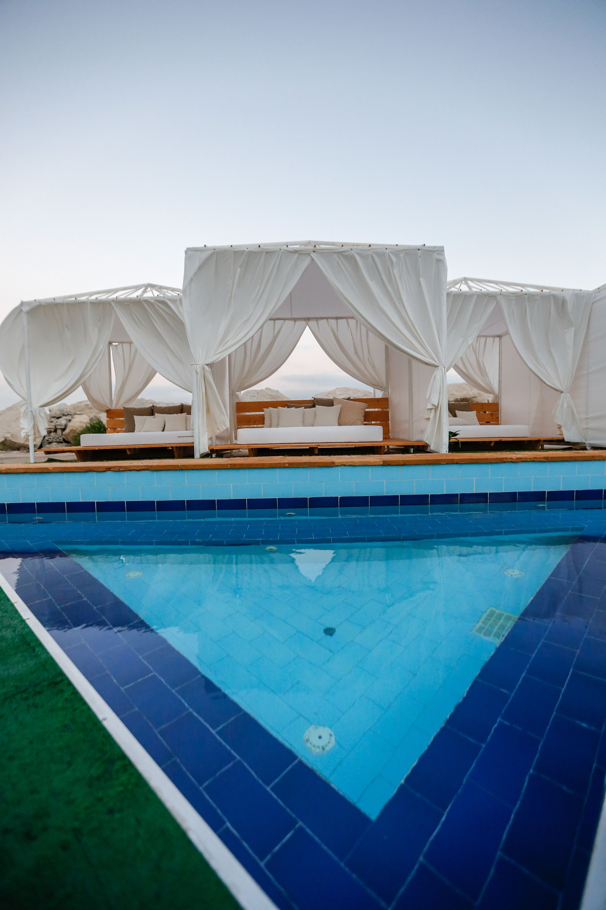 A pool area with white canopies and lounge chairs.