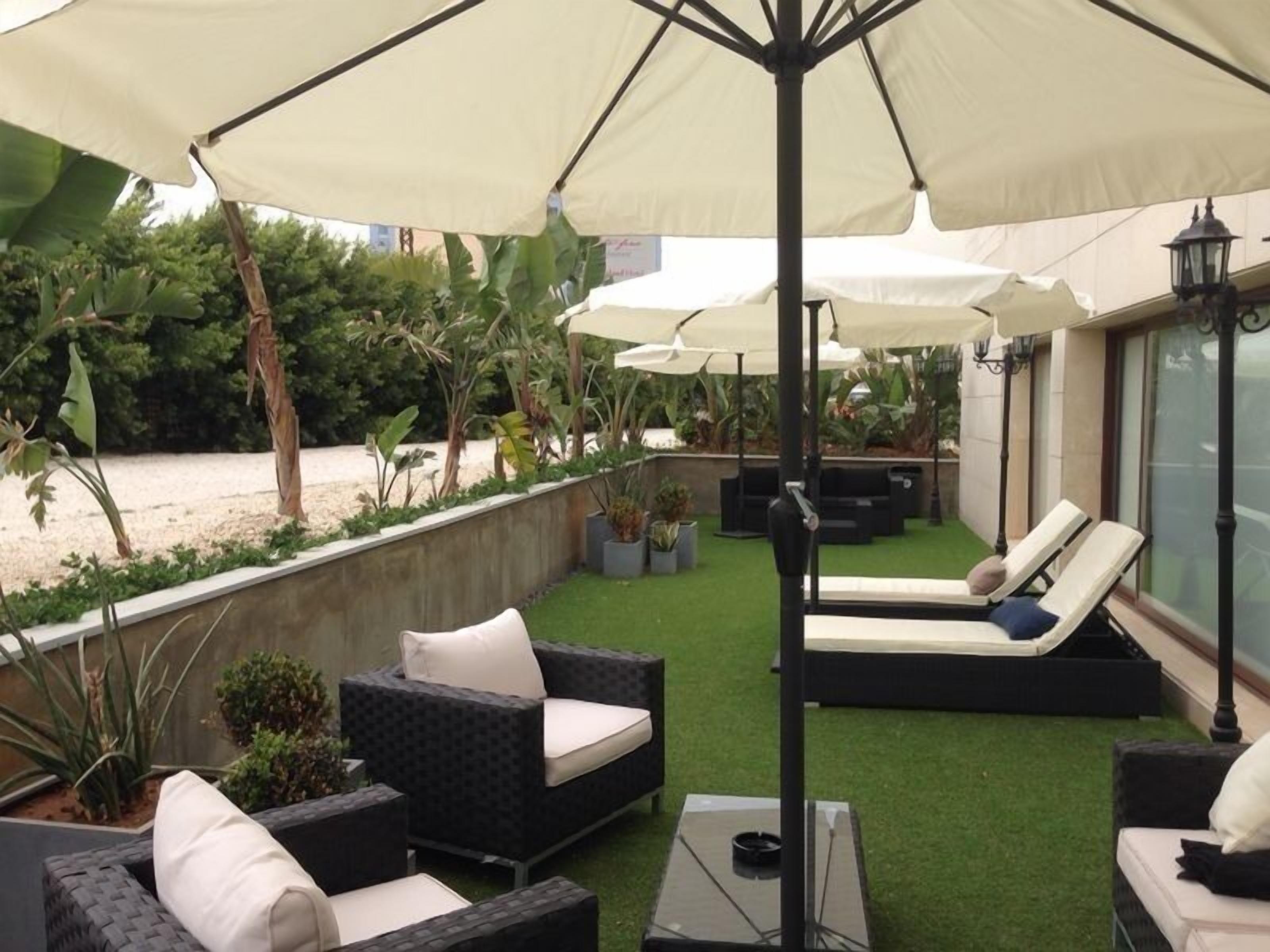 A patio area with outdoor seating, including sofas and chairs, under large umbrellas.