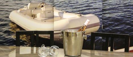 A glass table with a metal bucket containing a bottle, two empty glasses, and a chair.