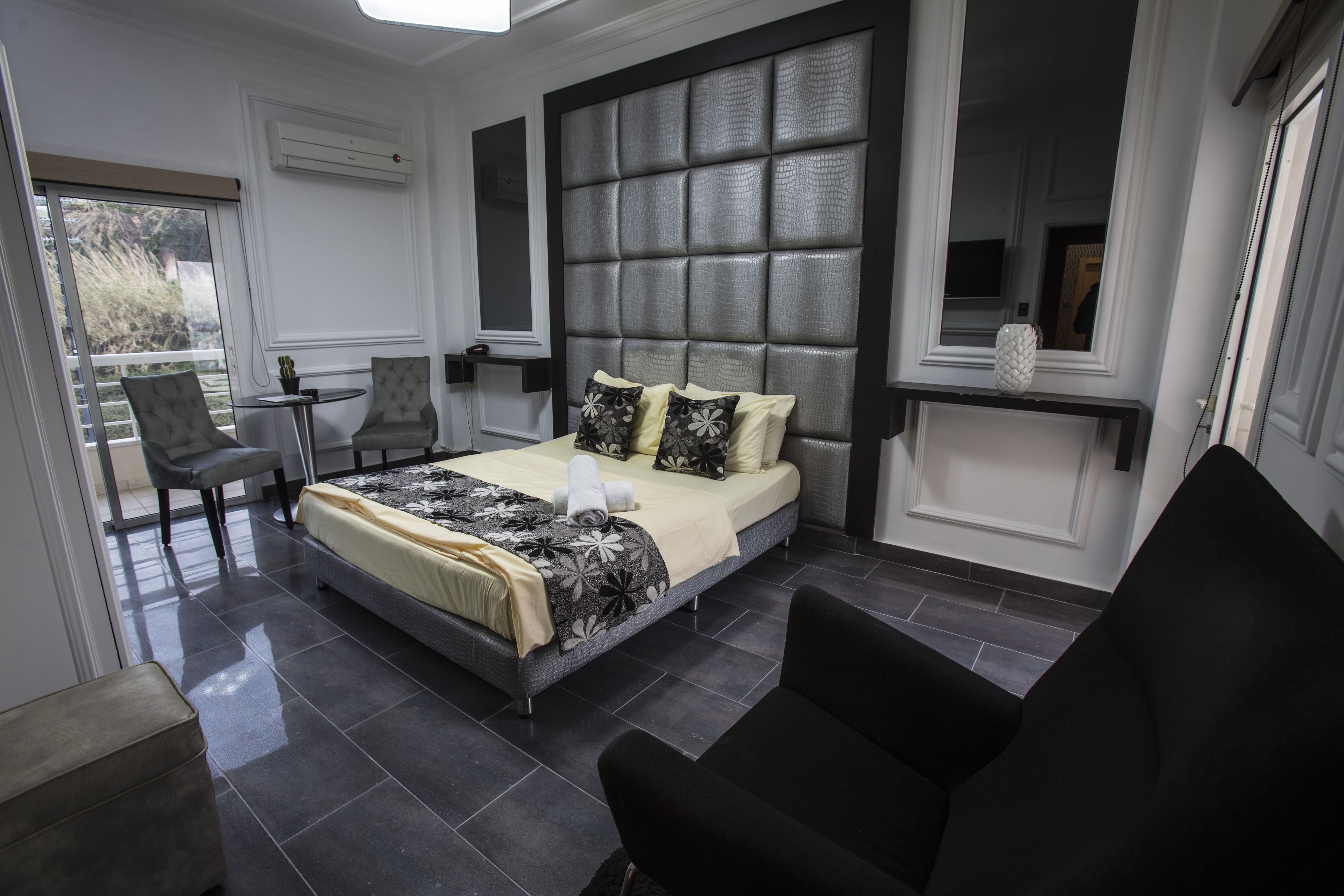 Un dormitorio moderno con una cama grande, una mesita, una silla y un sofá.