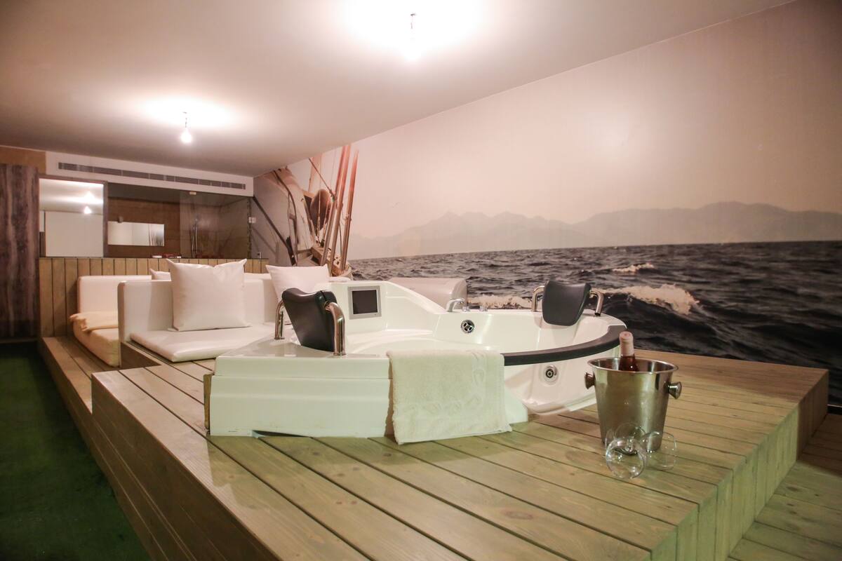 L'intérieur d'un bateau comprenant un coin salon, un jacuzzi et une vue sur la mer.
