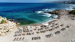A pebble beach with sun loungers and umbrellas, overlooking the sea. - Four Seasons Halat (Halat)