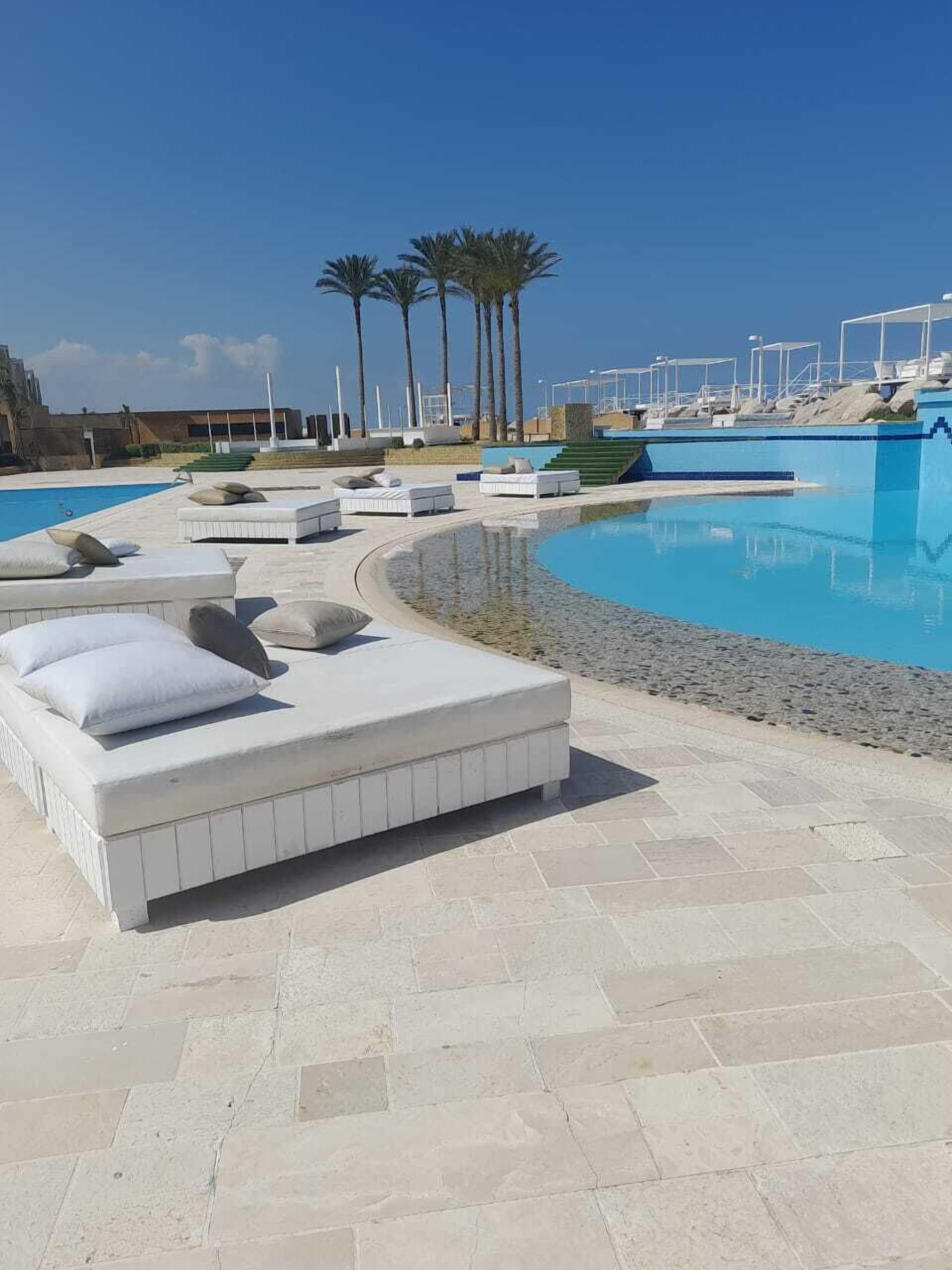 Ein Poolbereich mit Liegestühlen und einem klaren, blauen Pool.