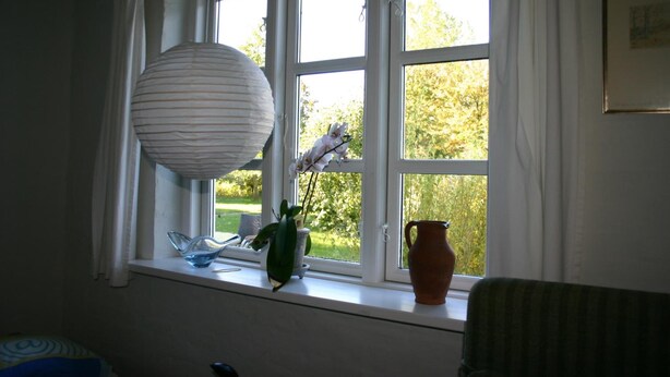 Een kamer met een vensterbank waarop een vaas, een schaal en een hanglamp staan.