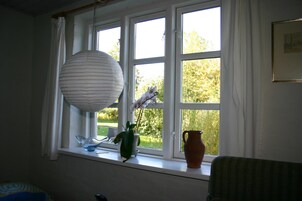 Una habitación con alféizar que sostiene un florero, un cuenco y una lámpara colgante.