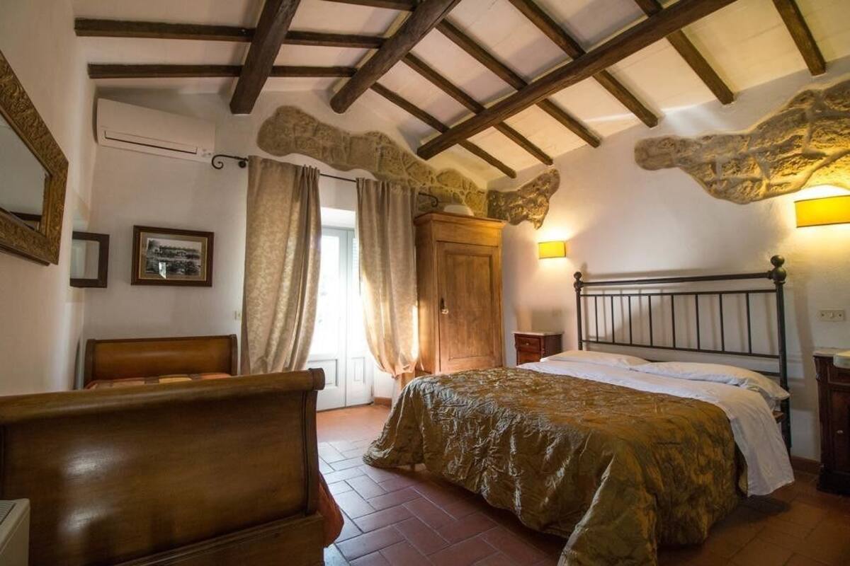 Une chambre à coucher avec un lit, des meubles en bois, un mur en pierre et une arche en pierre.