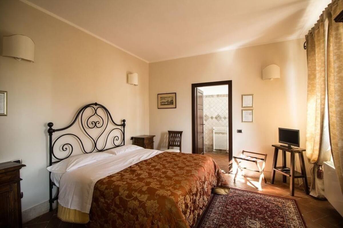 Une chambre dotée d’un grand lit, de tables de chevet, d’une chaise, d’un téléviseur et d’une porte donnant sur un espace extérieur.